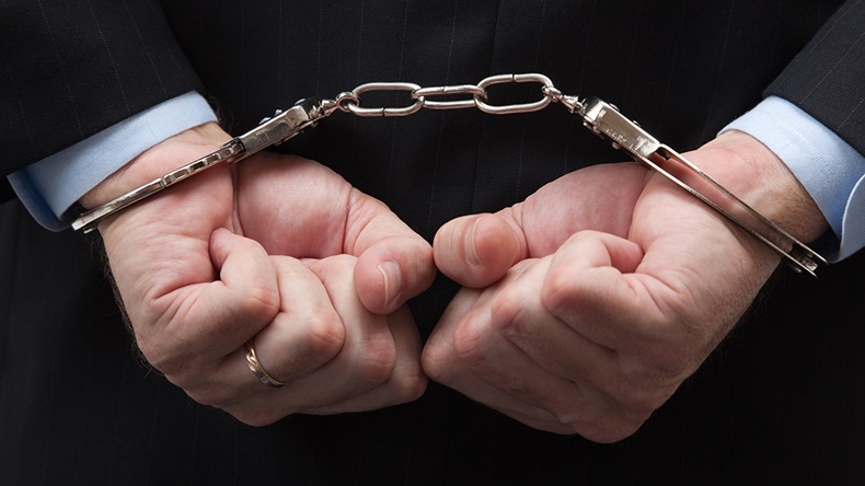 Businessman handcuffs (Mike Flippo/Shutterstock.com)